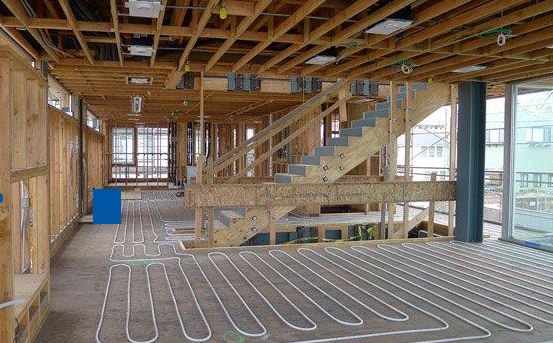 Rows of in-floor heating loops laid across a concrete subfloor in a house under construction
