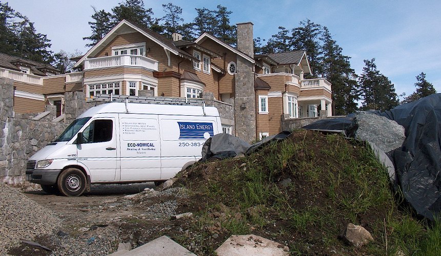 The white Island Energy van, lettered with the company logo, parked on a job site in front of a large shingled house